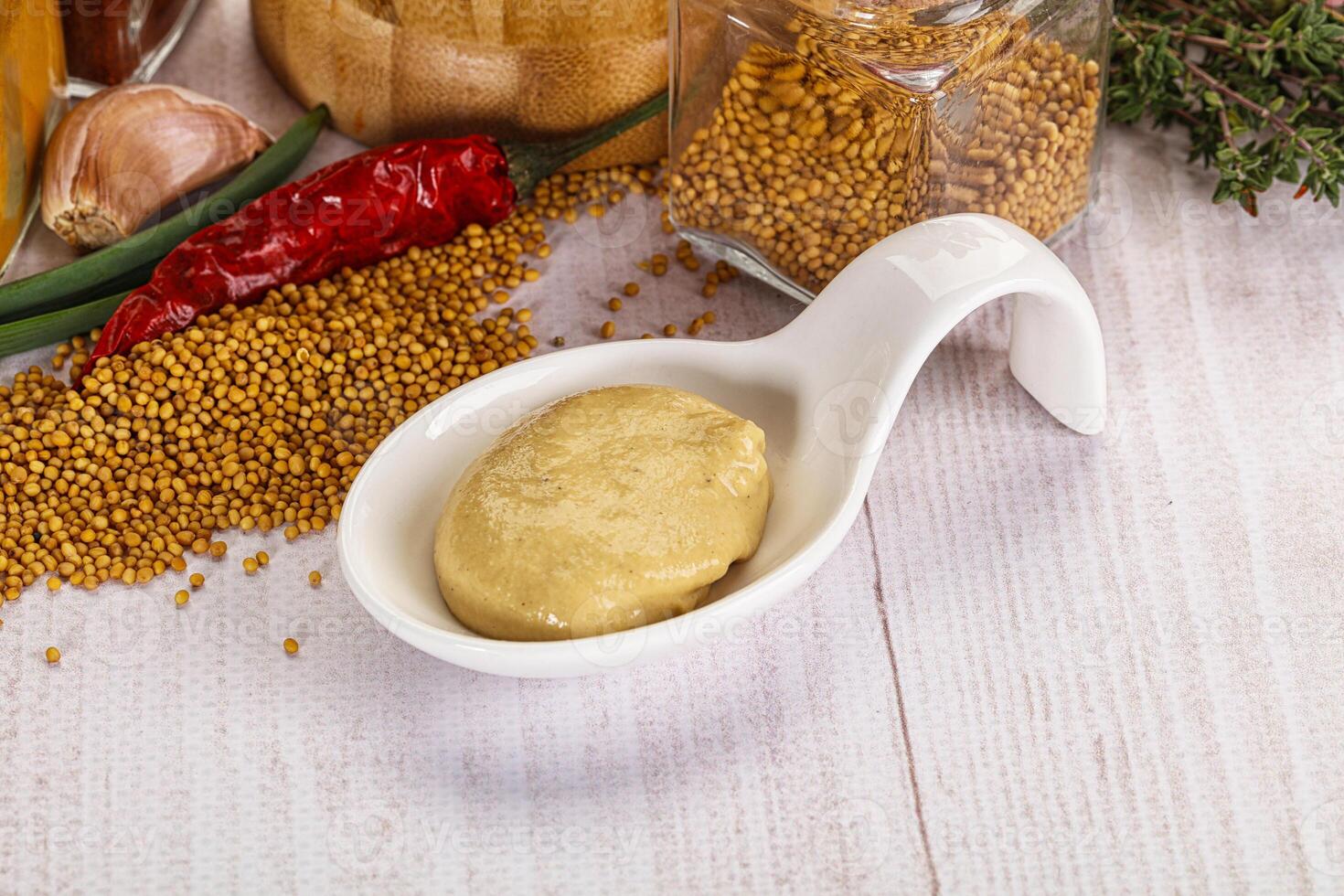 A white measuring spoon with a scoop of mustard on it photo