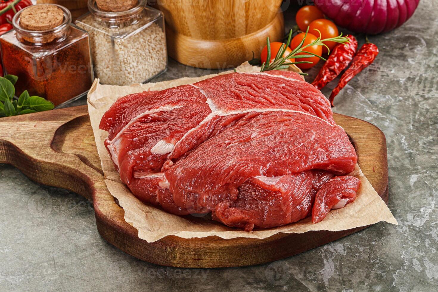 A raw beef steak on a cutting board with spices and other ingredients photo