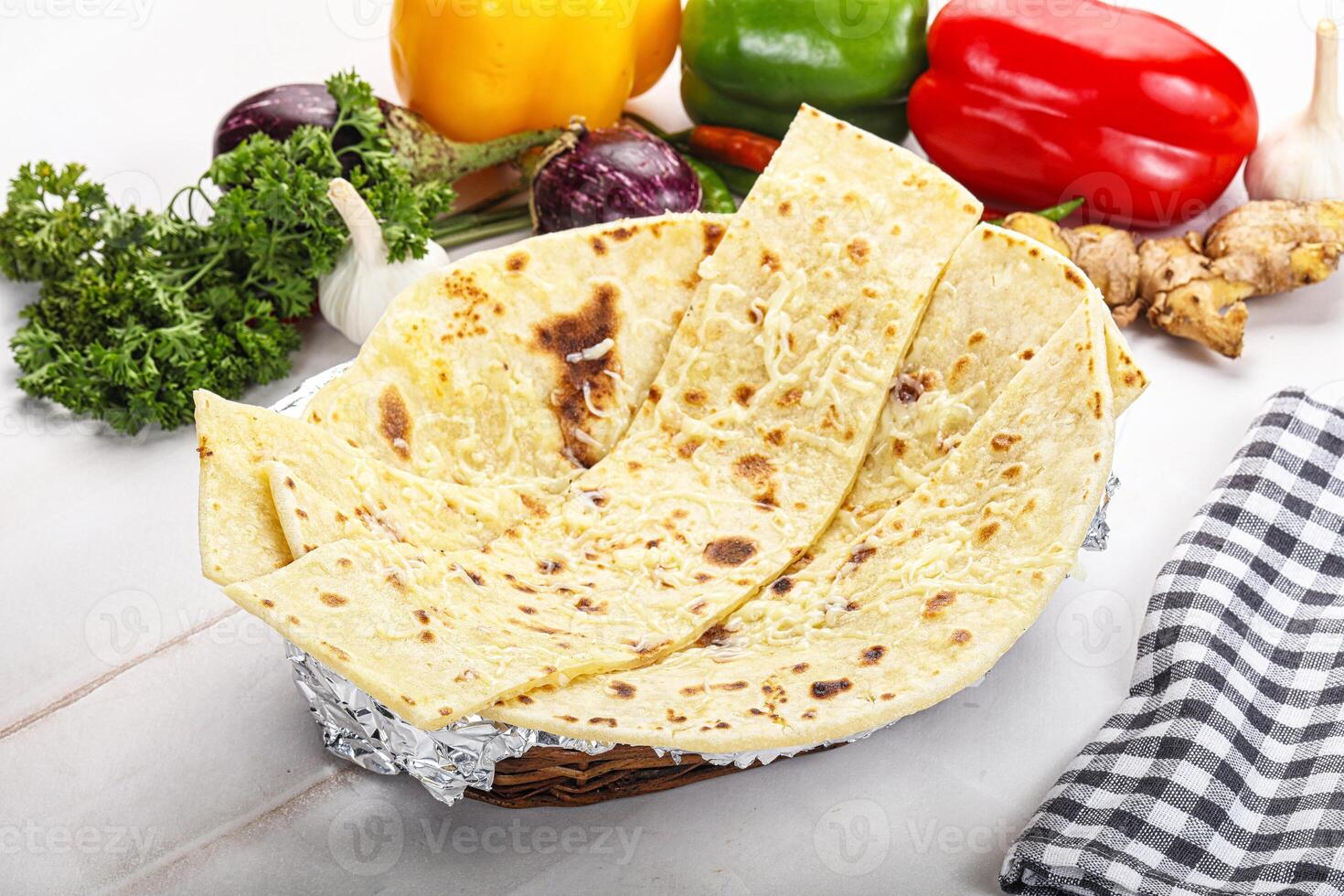 A basket of tortillas on a table with vegetables and other food photo