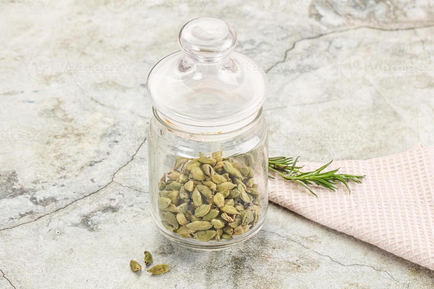 A jar filled with green seeds and a rosemary sprig photo