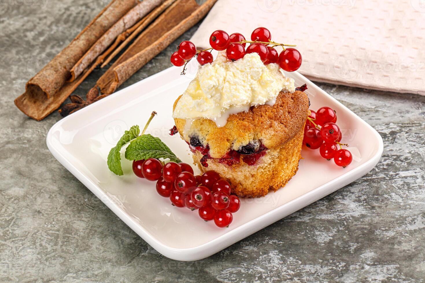 A muffin with cream and berries on a plate photo