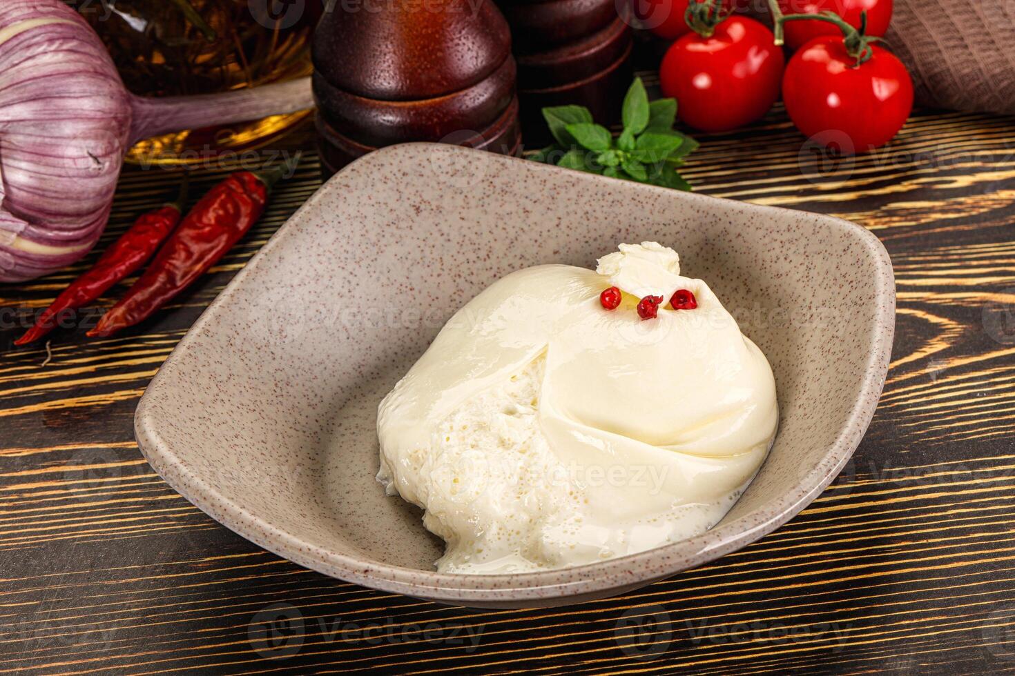 A bowl of ice cream sitting on a table next to a bowl of tomatoes and garlic photo
