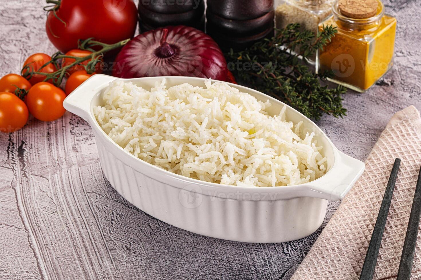 A white dish with rice and vegetables on a table photo