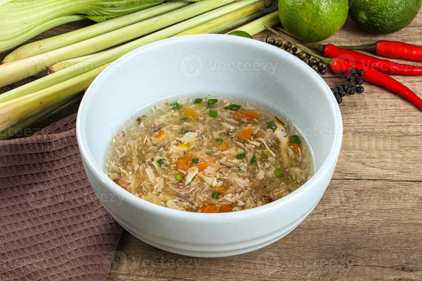 A bowl of soup with vegetables and a towel on a table photo