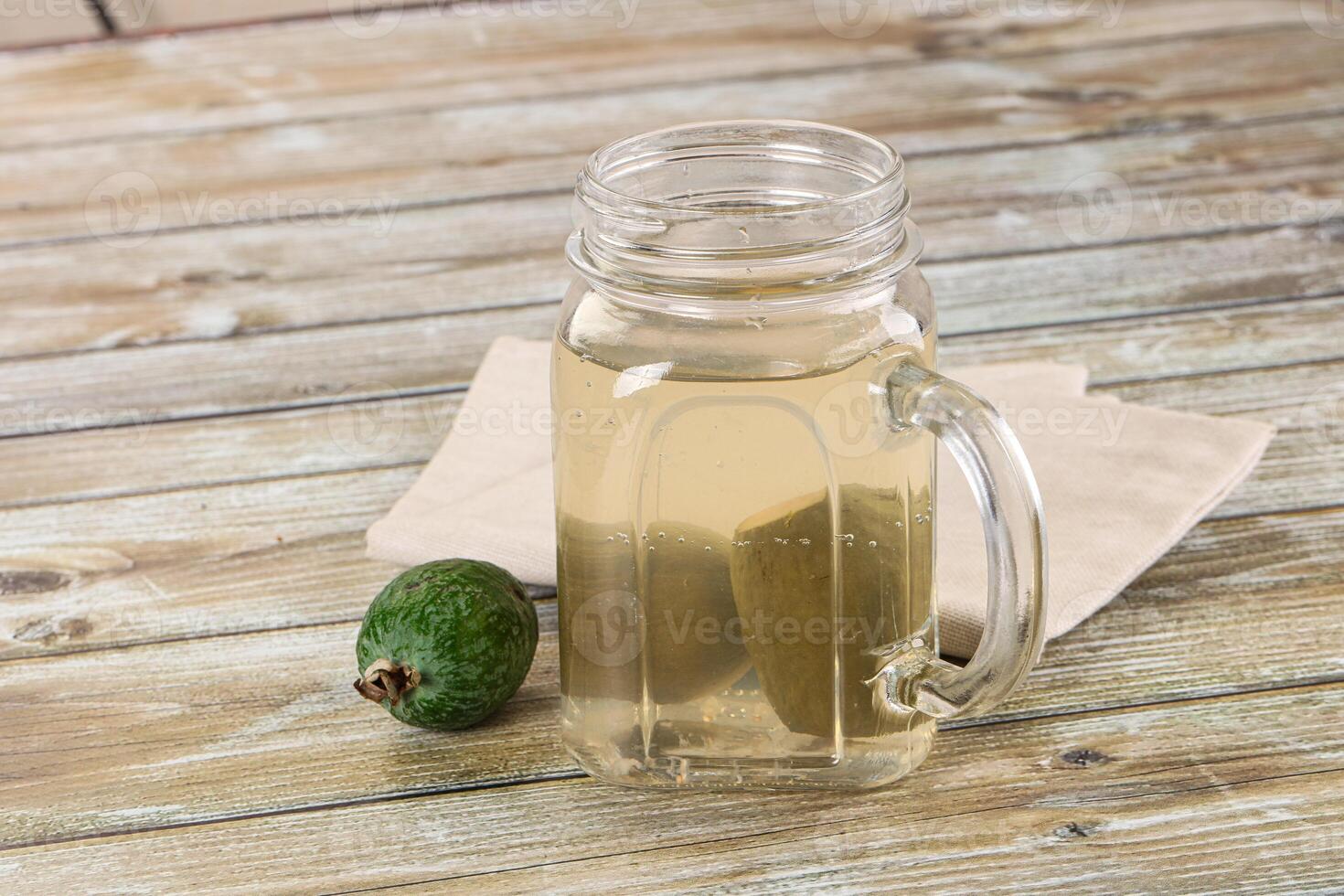 A glass jar with a lime and a napkin on a wooden table photo