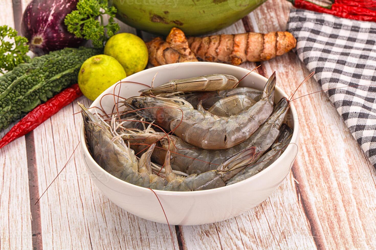 A bowl of shrimp sitting on a table next to other vegetables photo