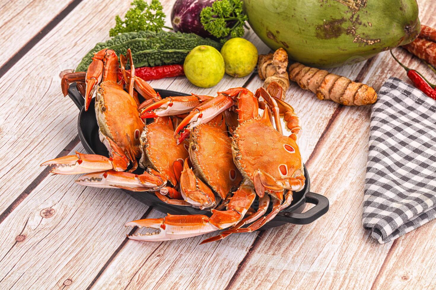 A bunch of crabs sitting on a table with other vegetables photo