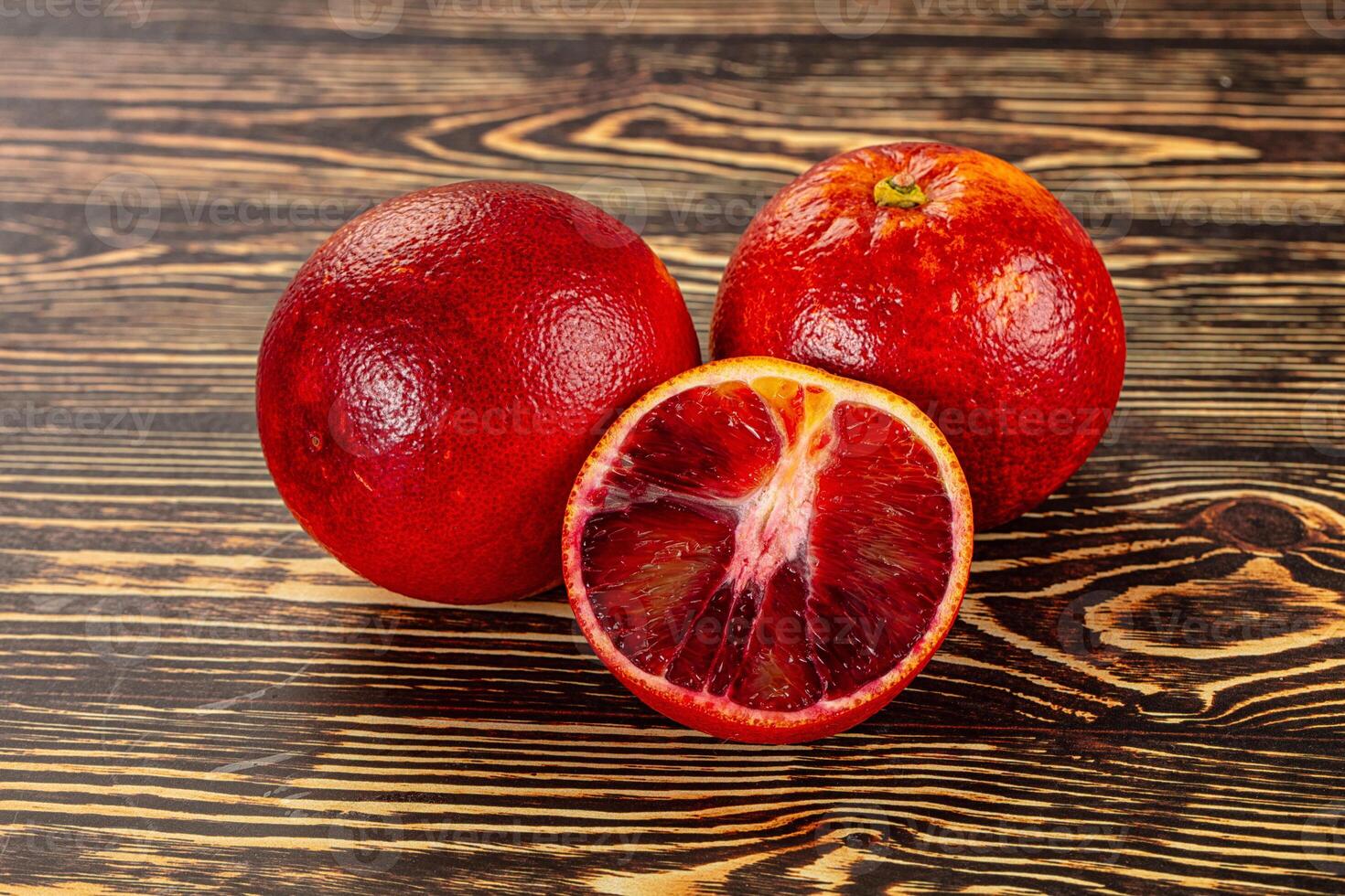 A close up of two blood oranges on a wooden table photo