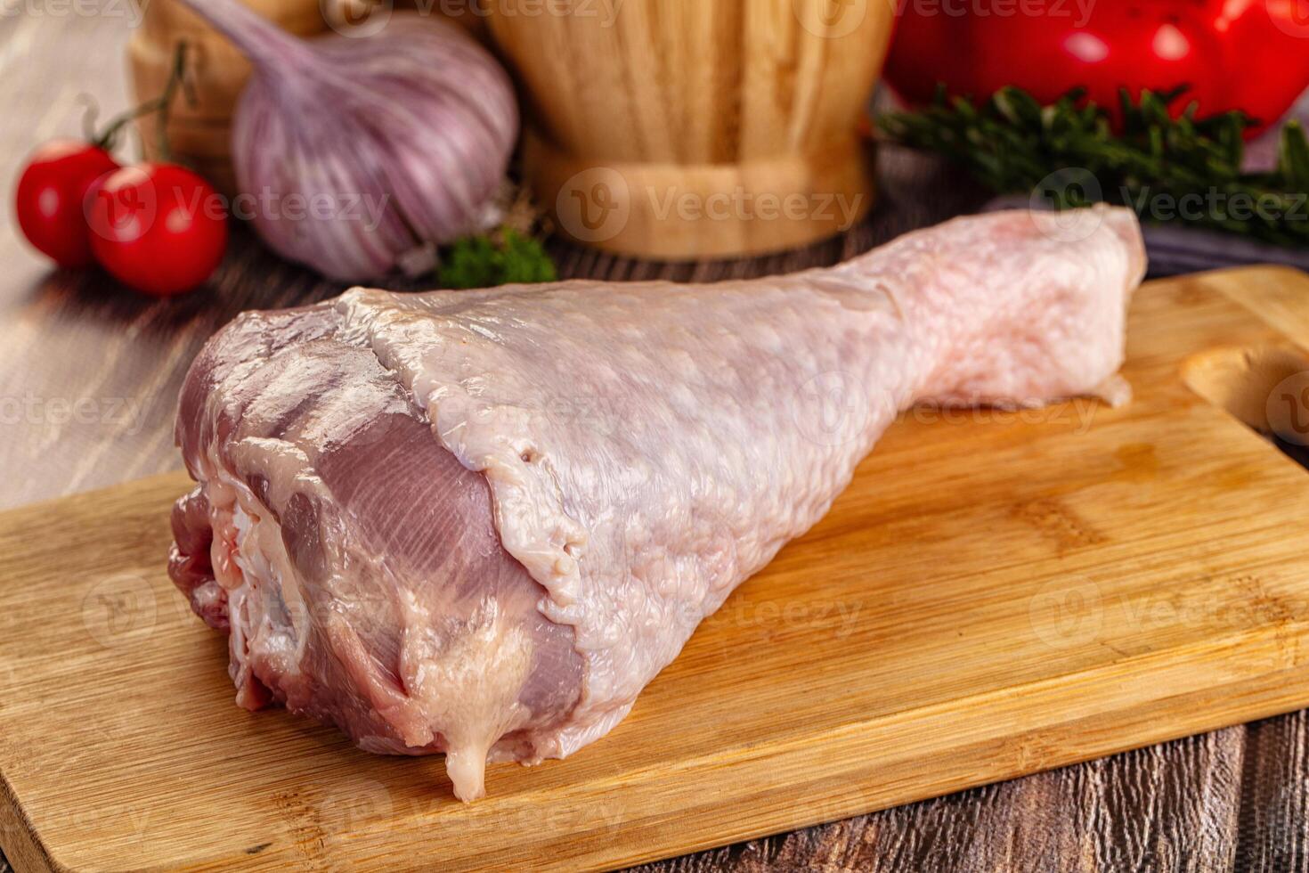 A raw chicken on a cutting board with tomatoes and herbs photo