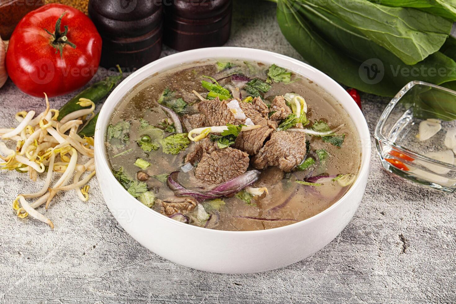 A bowl of soup with meat and vegetables on a table photo