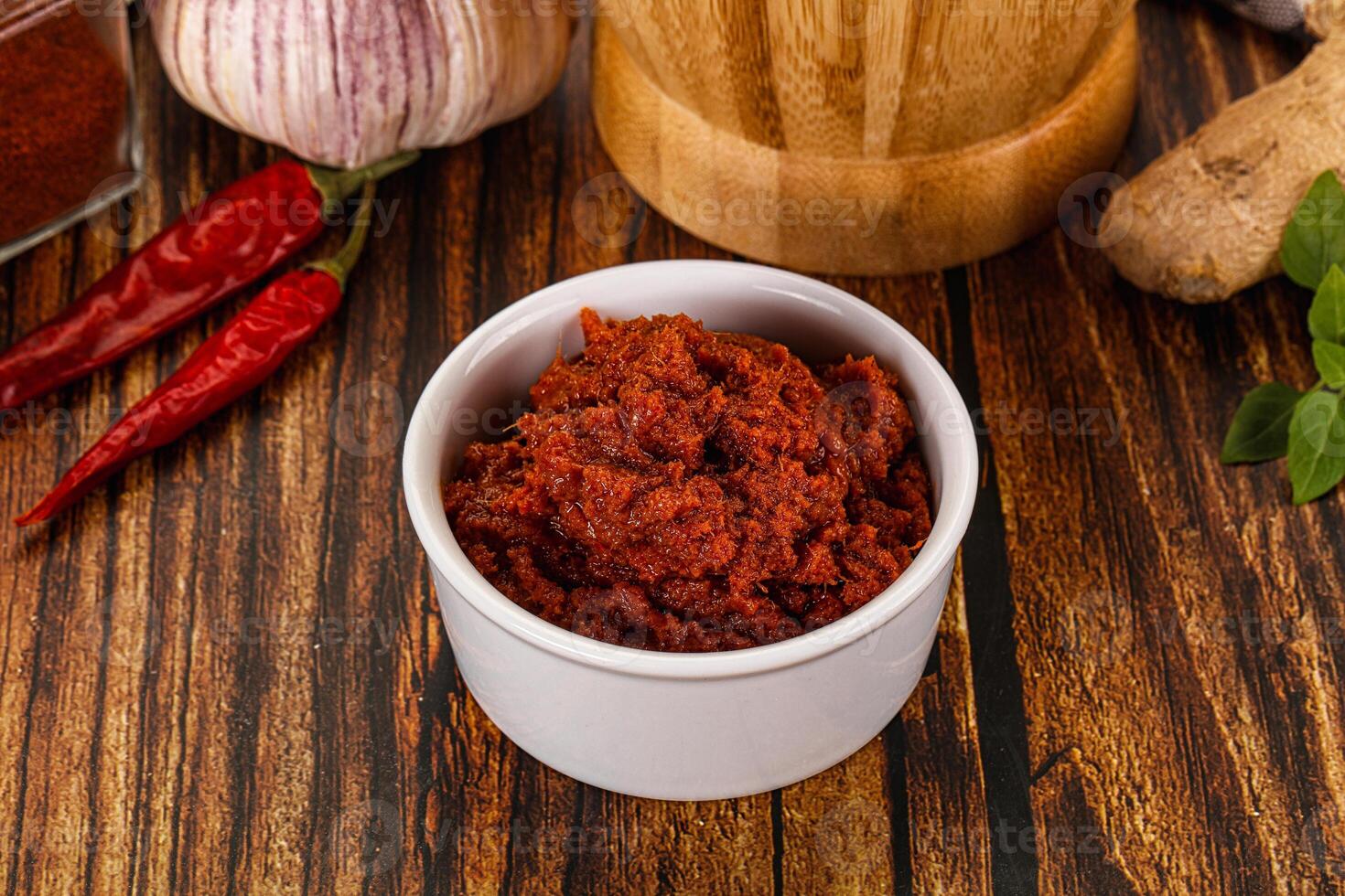 A bowl of chili and spices on a wooden table photo