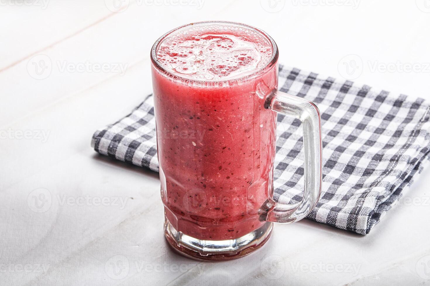 A glass of red smoothie on a table photo