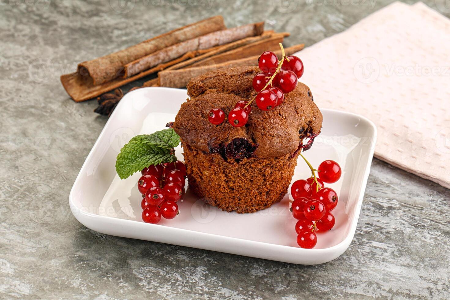 A muffin with berries and cinnamon sticks on a plate photo