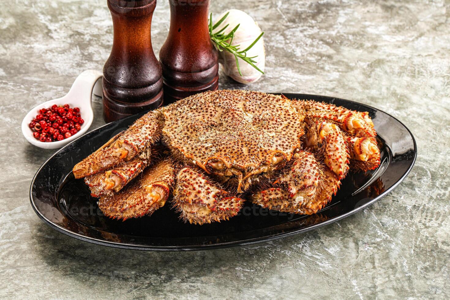 A large crab on a plate with a pepper and salt photo