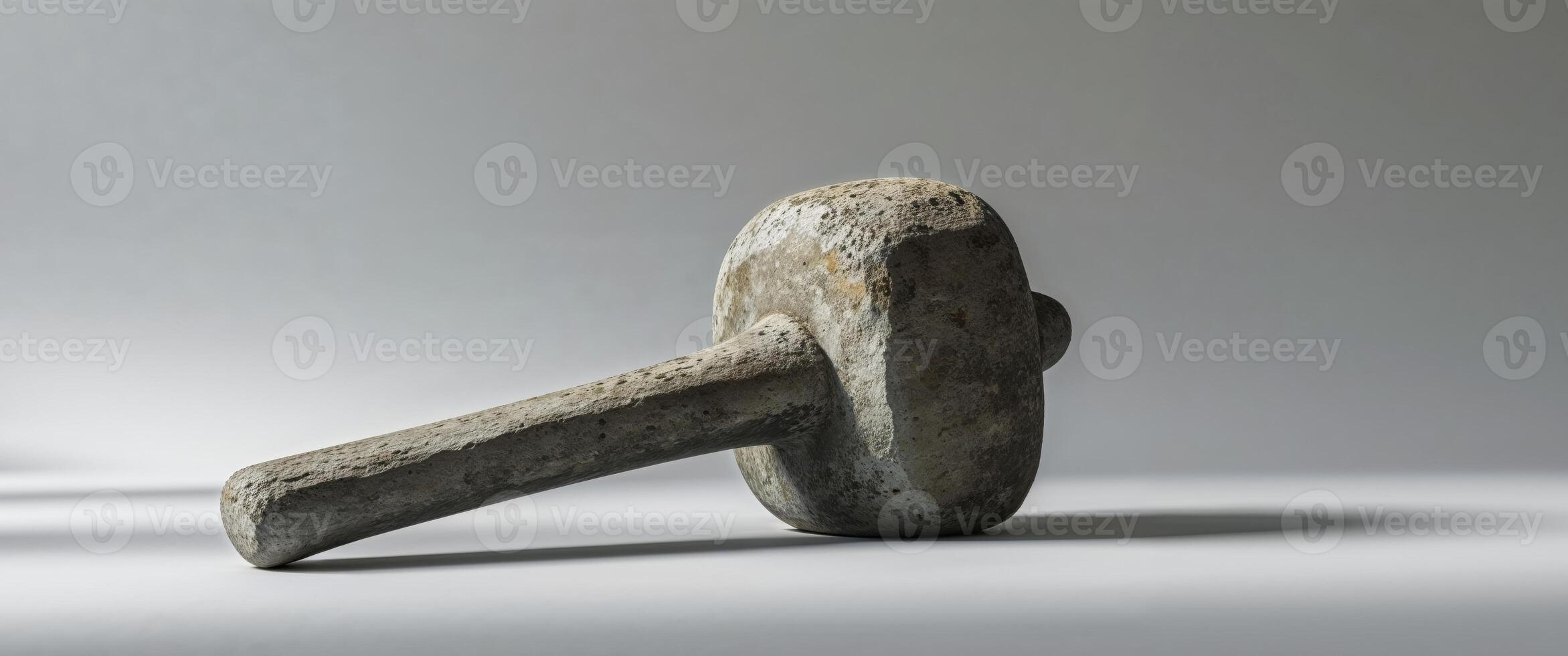 Old stone mace laying horizontally on a gray surface photo