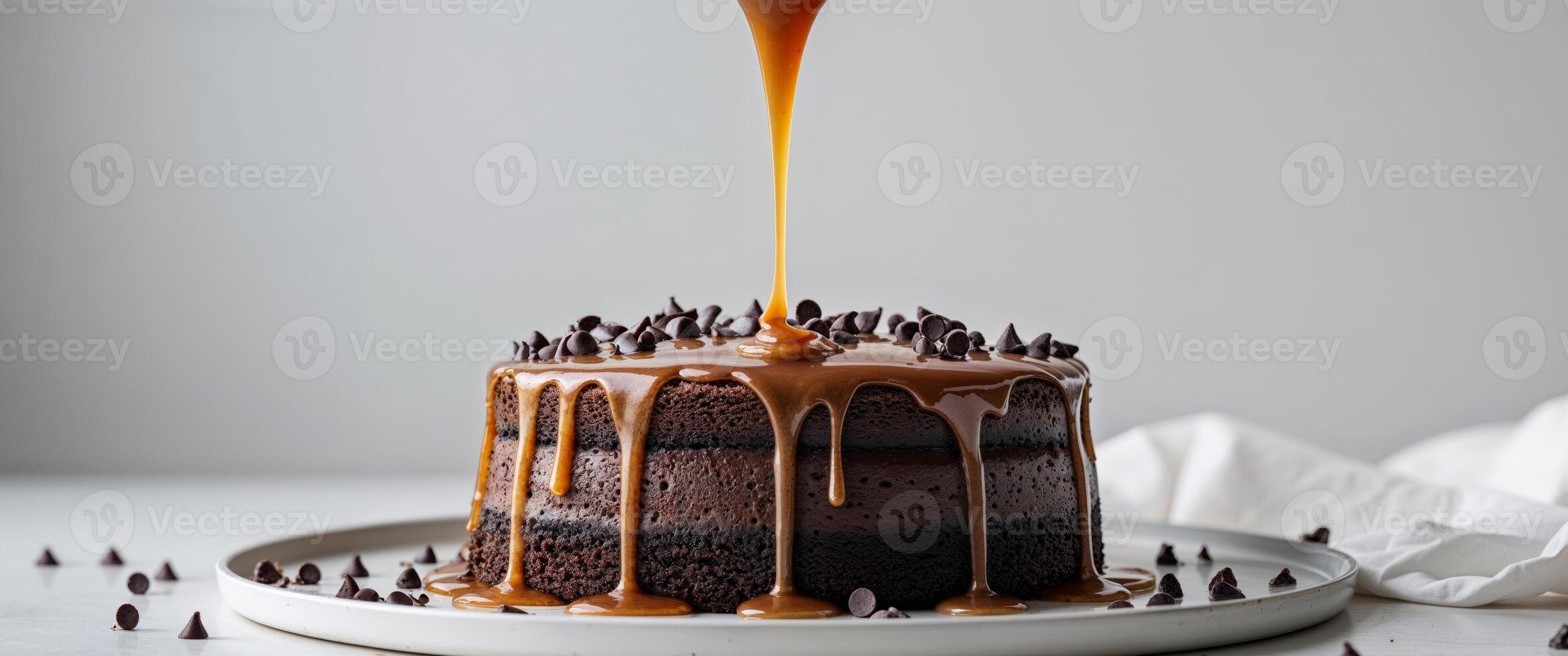 A chocolate cake with caramel sauce being poured over it photo