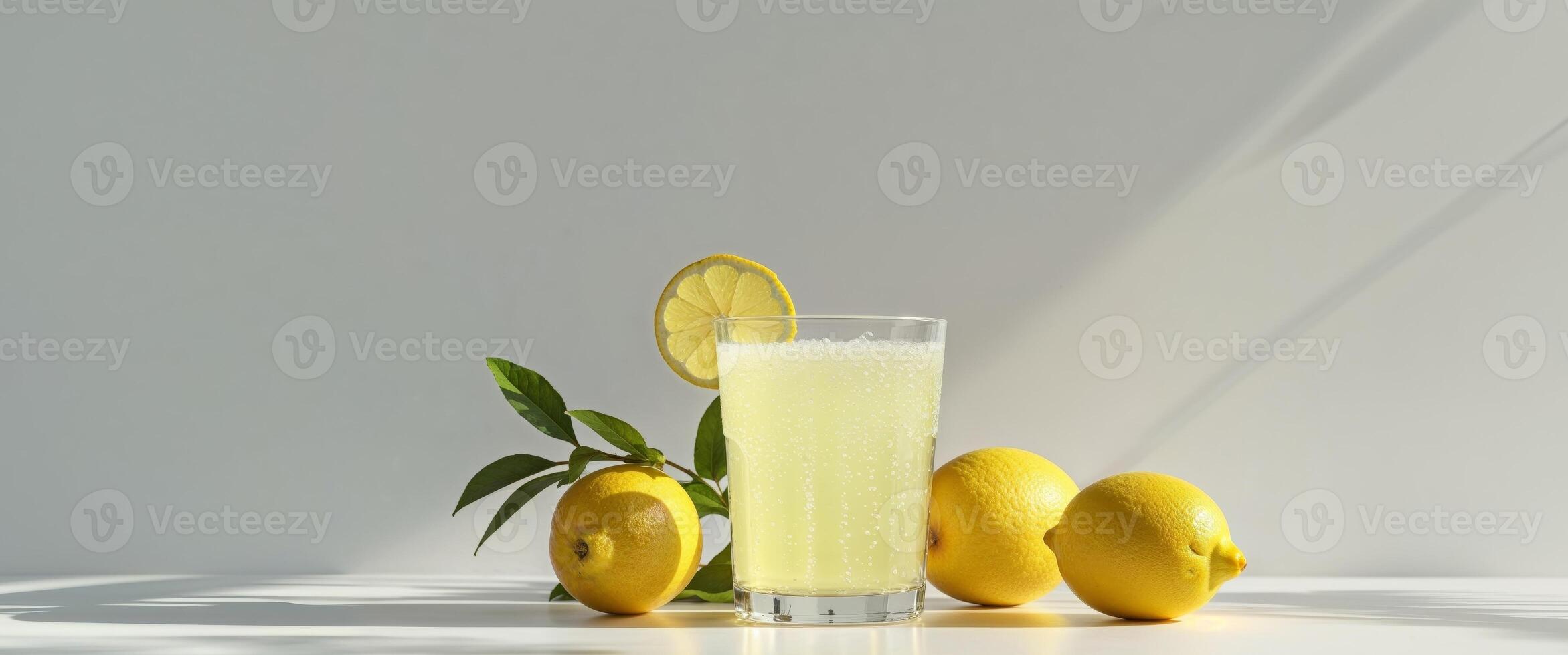 Lemon juice in a glass with lemons on a white table photo