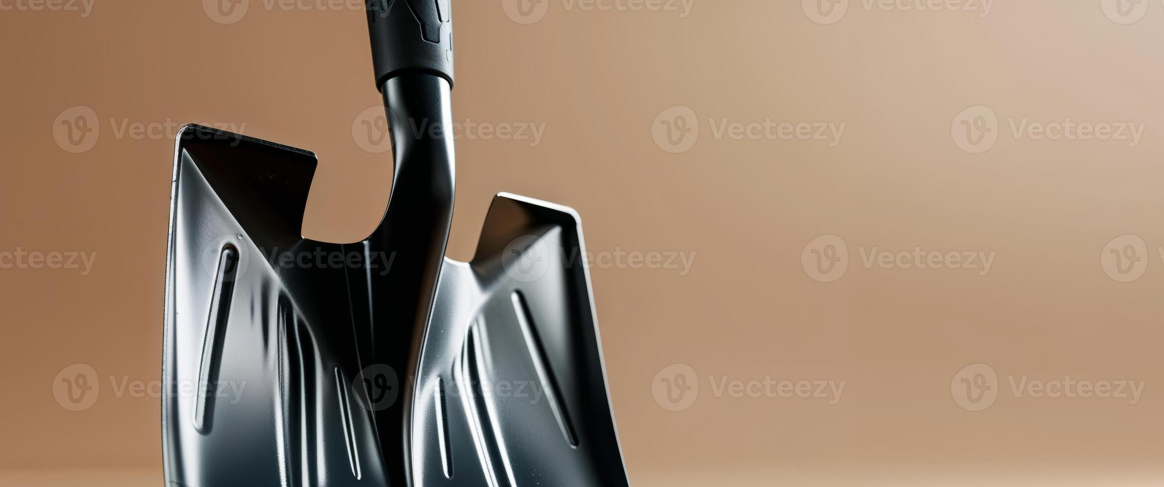 a close up of a black shovel on a tan background. photo