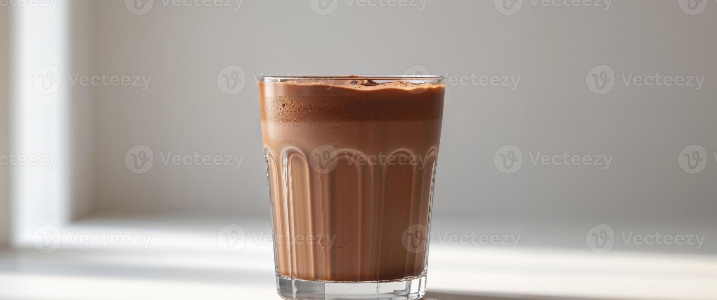 A glass of chocolate milk sitting on a table photo