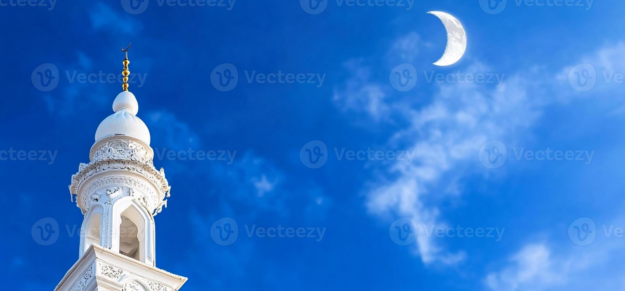 A minaret against a blue sky with a crescent moon. photo