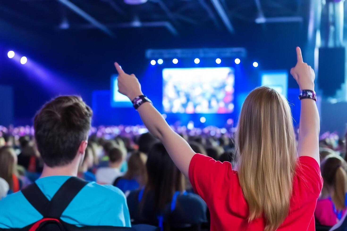 Excited audience at a large event, pointing at the stage photo
