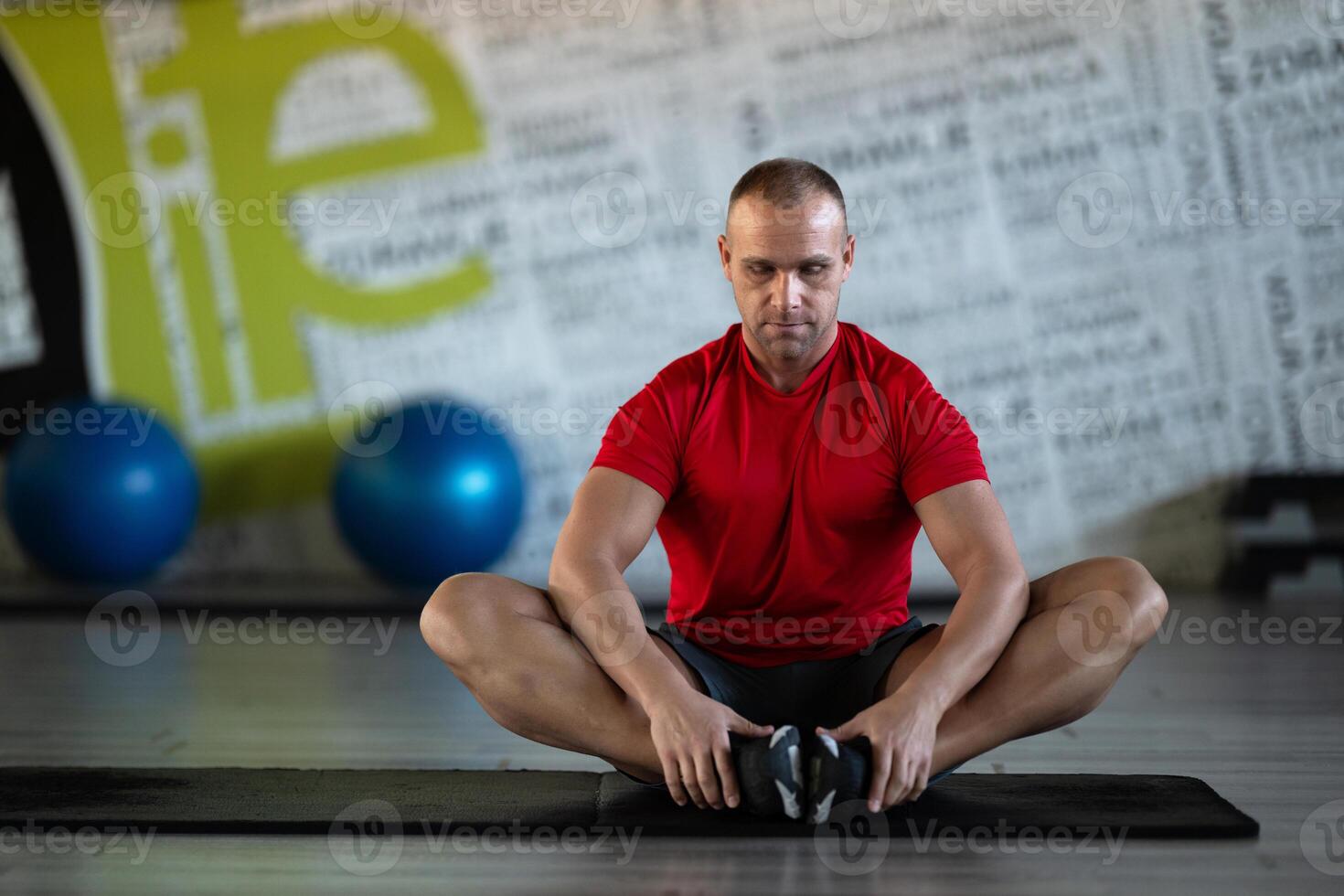 A fitness man stretches in the gym after an intense workout, focusing on recovery and flexibility. photo