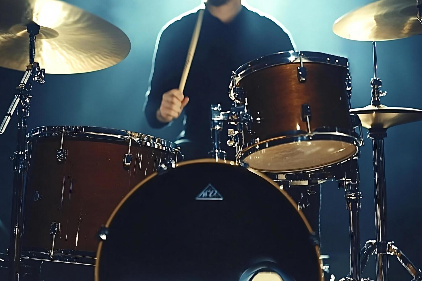 Drummer playing drums on stage with blue backdrop photo