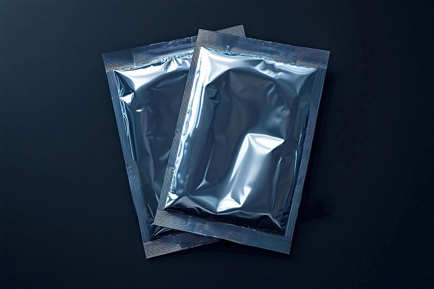Two foil packaging sachets lying on dark background photo