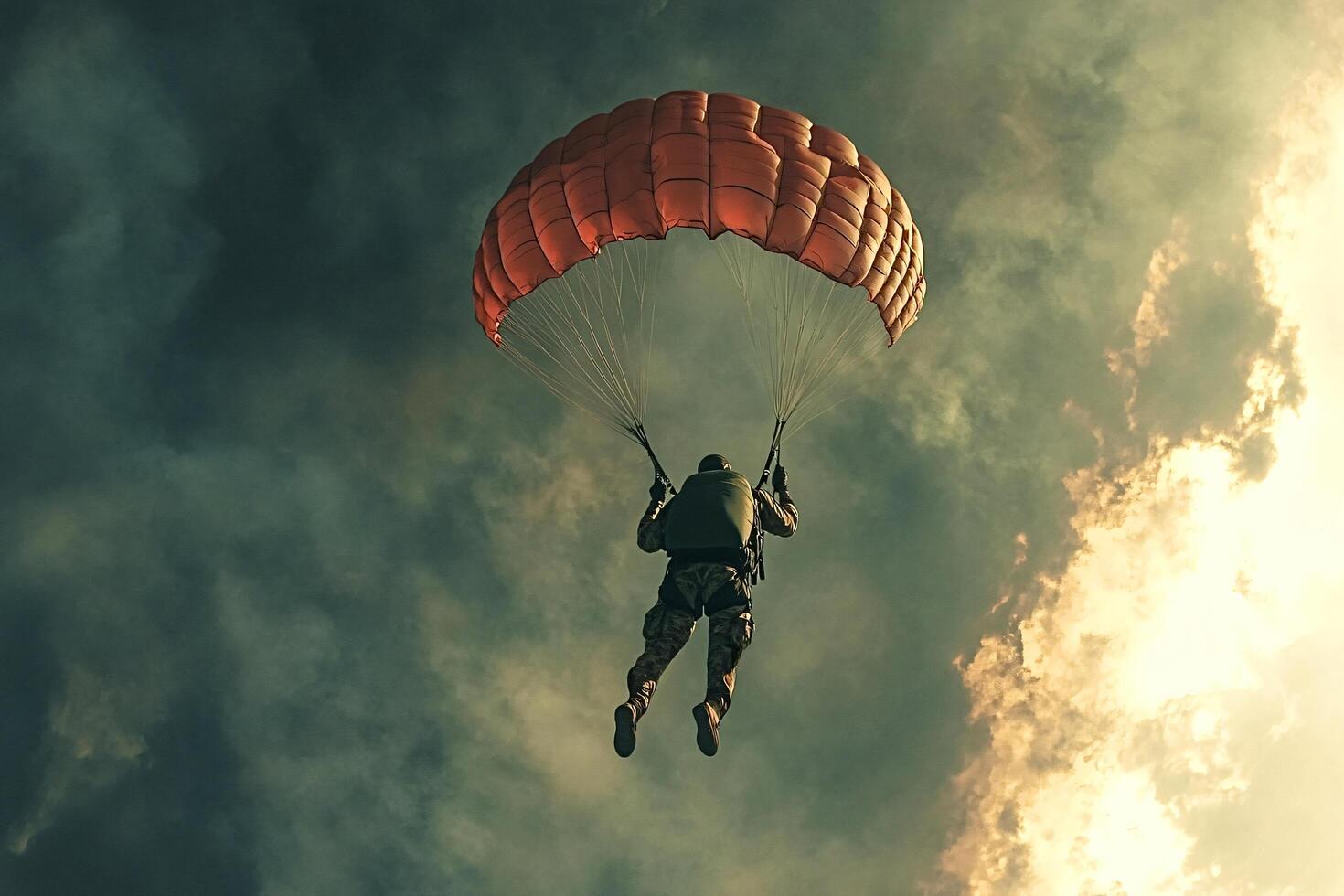 Military paratrooper descending with red parachute in cloudy sky photo