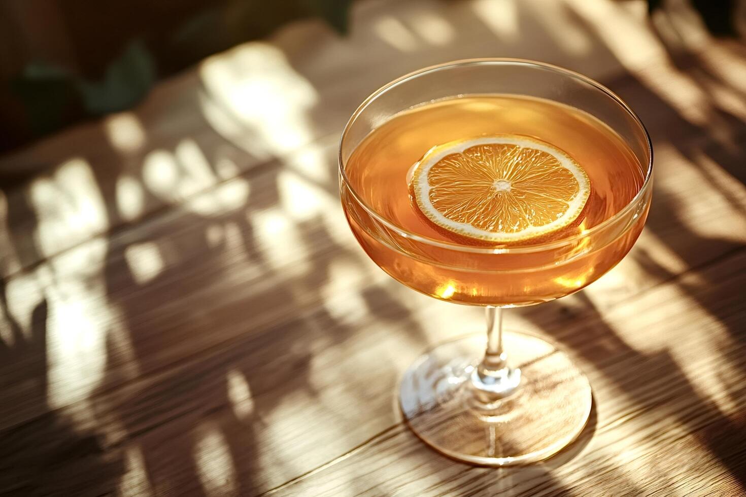 Orange cocktail sitting on wooden table in sunlight photo