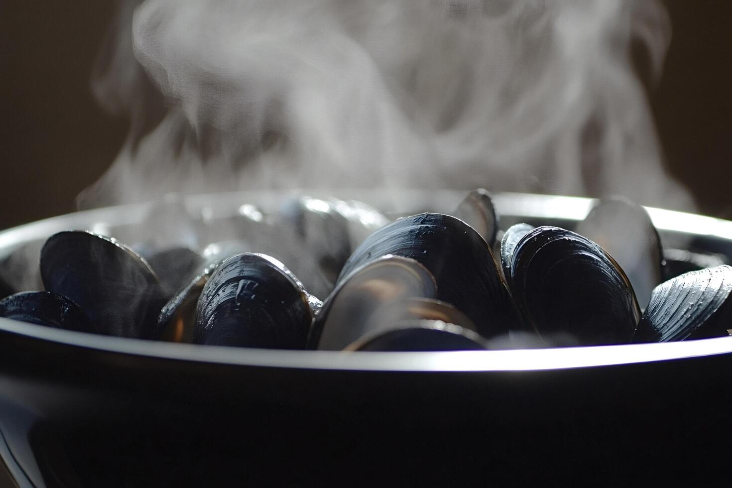 Steaming mussels releasing delicious aroma in black bowl photo
