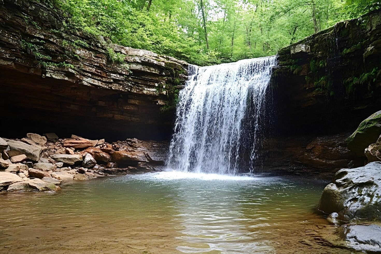 Waterfall cascading from a rocky cliff into a clear pool in the forest photo
