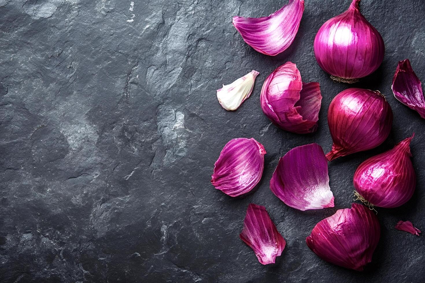Fresh red onions and loose skins resting on dark stone surface photo