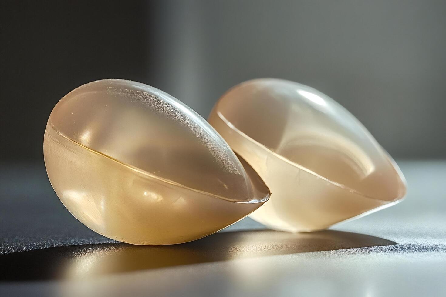 Silicone breast implants resting on a reflective surface photo