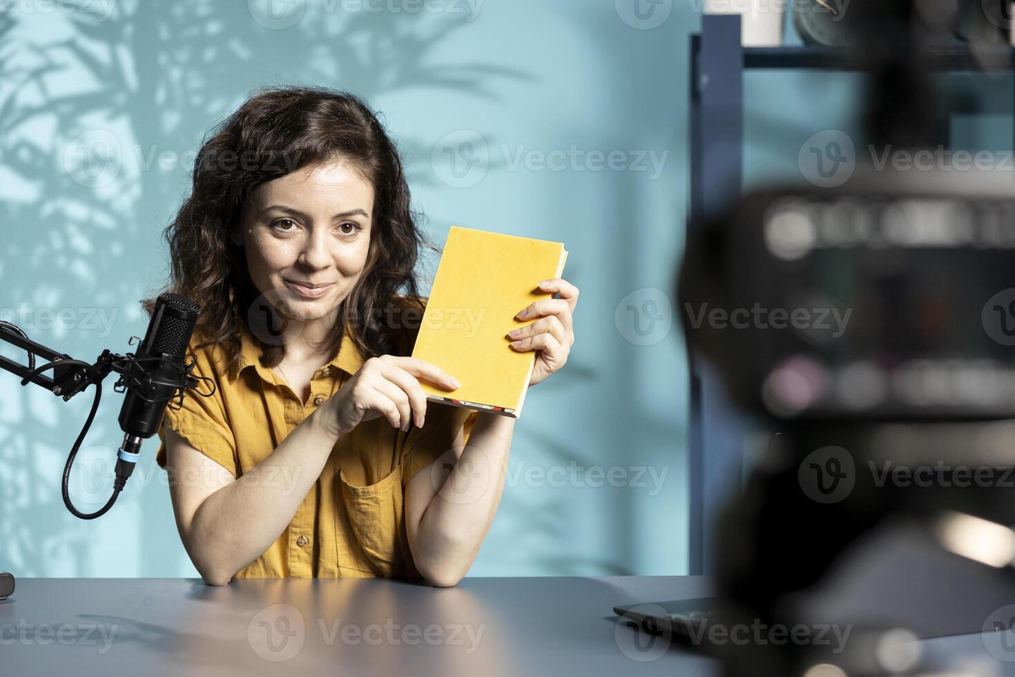 Happy online show host reading and recommending best reviewed books of the year. Jolly content creator in studio doing novel summaries for interested readers, speaking in professional mic photo