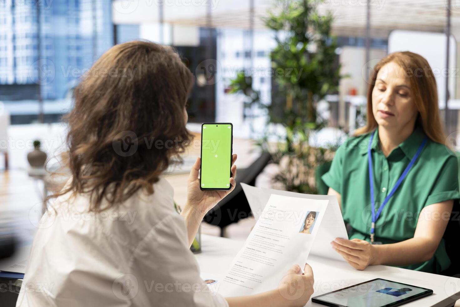 HR expert using mockup smartphone while vetting applicants to ensure skills match role needs. Headhunter talking with person coming for interview, using green screen mobile phone photo