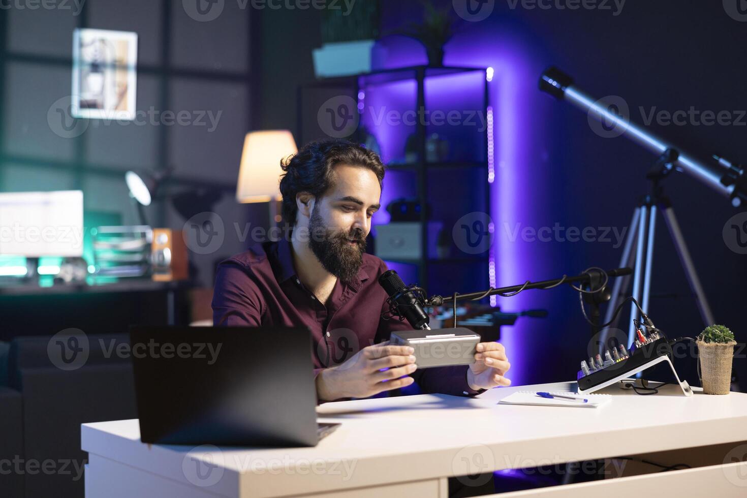 Happy internet star doing technology review of Bluetooth portable speaker for online platforms channel. Smiling influencer presenting music playing device to his viewership photo
