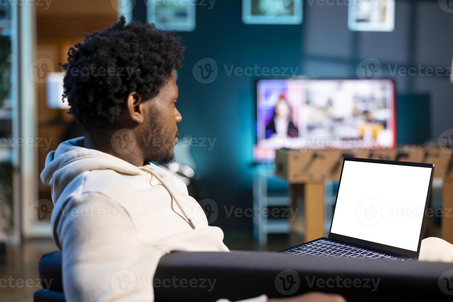 Man relaxing in warm living room by watching funny movie on mockup laptop. Person enjoying leisure time in neon illuminated apartment, looking at films on isolated screen notebook photo