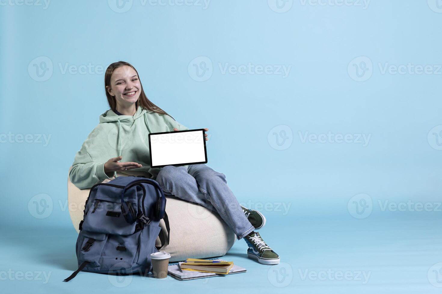 Portrait of joyous teenager reviewing tablet with mockup display, studio backdrop. Radiant young girl offering feedback on isolated screen digital device, studio background photo