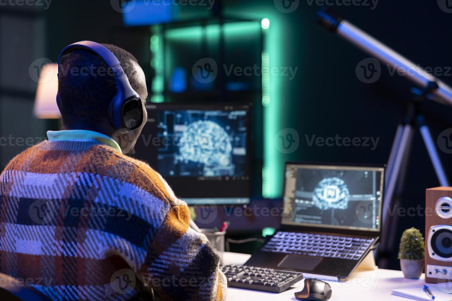 Professional male developer manages neural network at desk, working with AI code on laptop. African american IT expert freelancer developing cyber security, creating secure database. photo