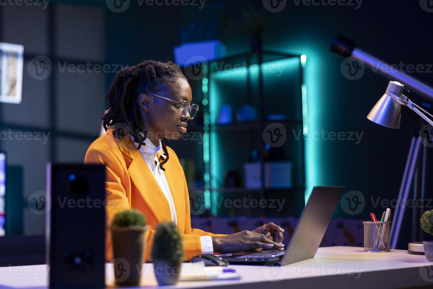 Woman wearing glasses using laptop in home office, checking emails displayed on screen, reading messages in inbox, composing and sending replies, managing electronic correspondence photo
