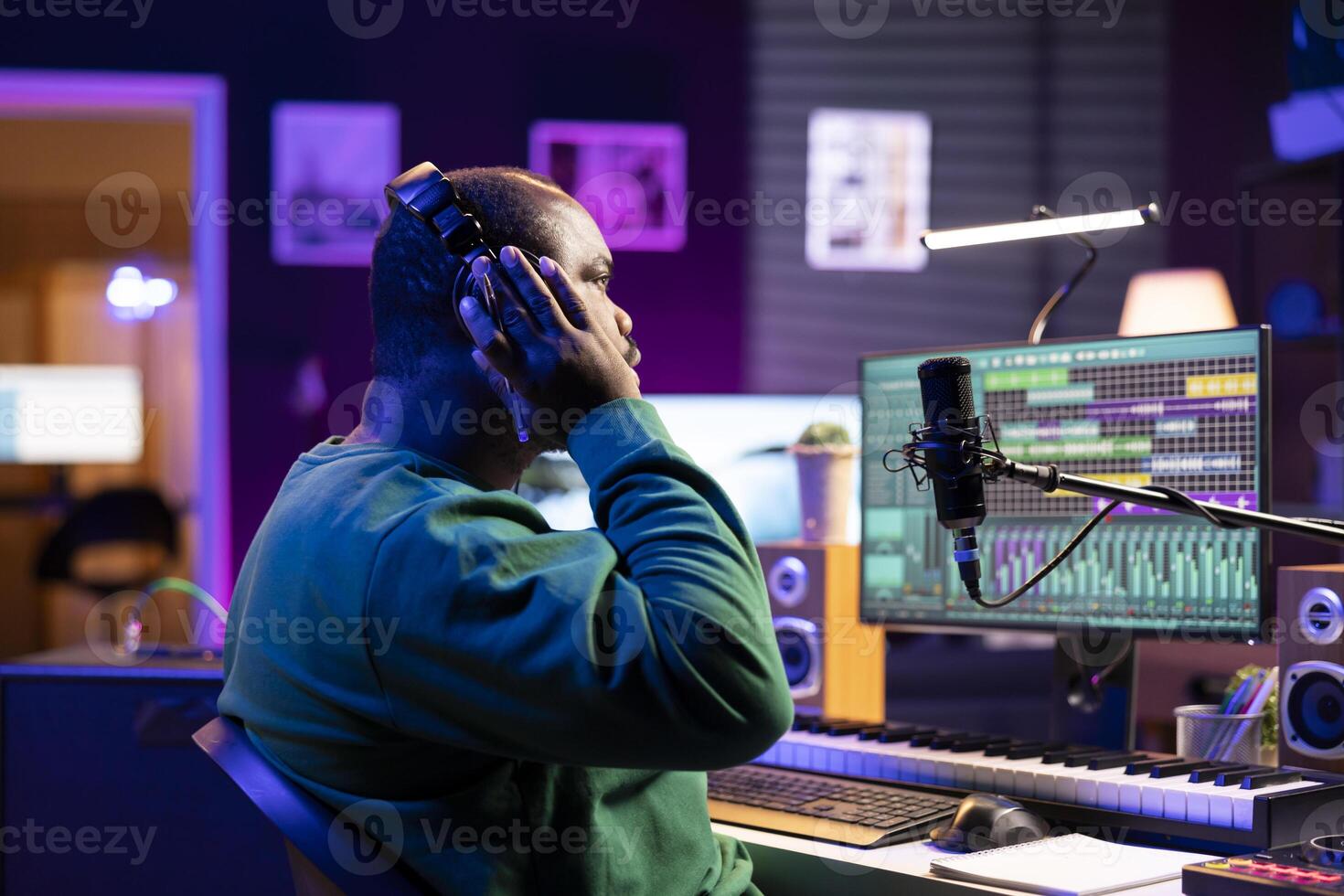 African american music producer listening to recorded song in home studio, making room for improvement and editing sound effects. Composer technician does mix and master with gear. photo
