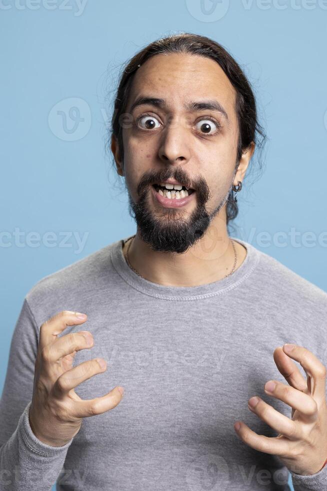 Frustrated angry person expressing his intense emotions and anxiety on camera, showcasing anger management issues and rage. Young adult being furious and irritated with something in studio. photo