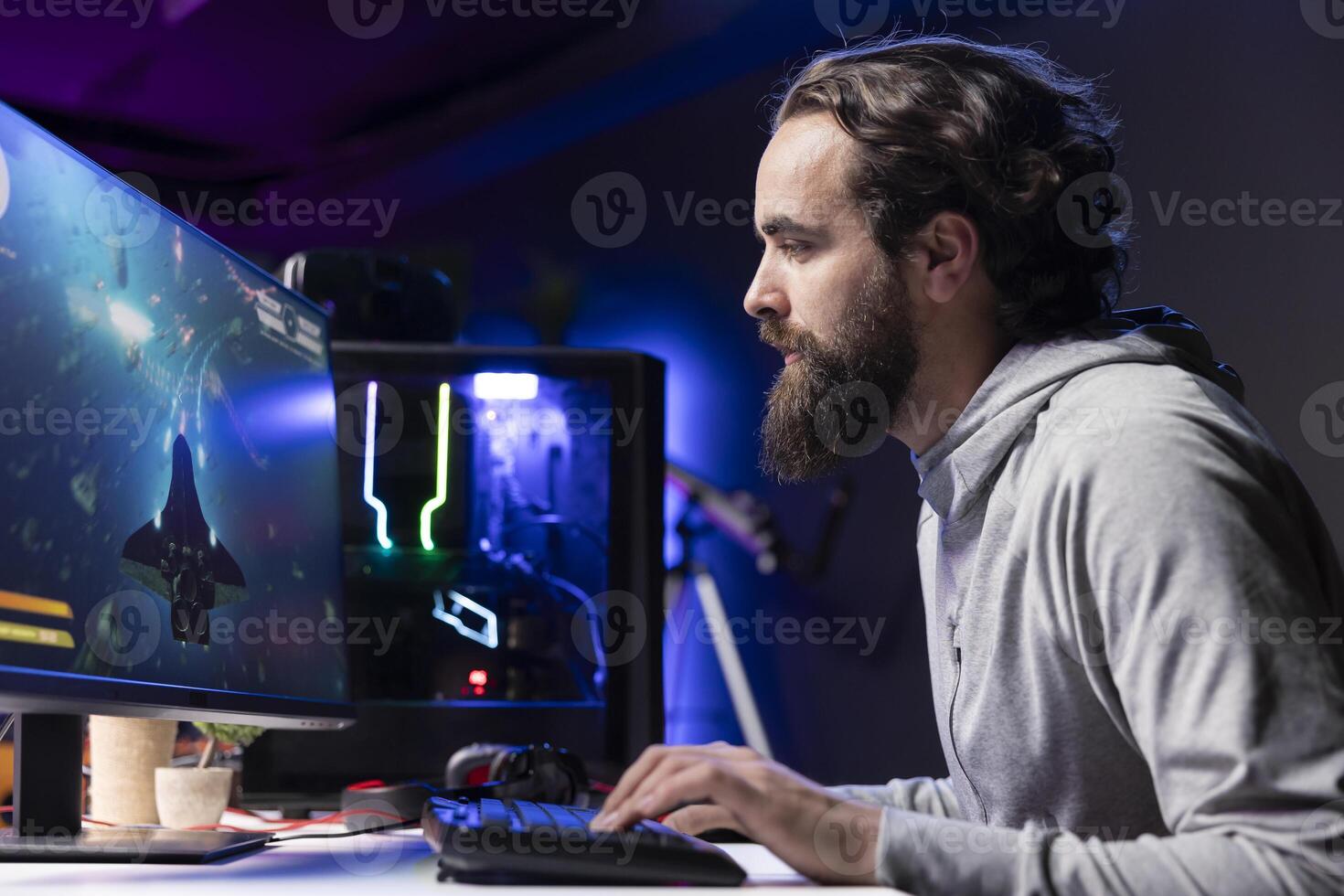 Man relaxing by playing science fiction galaxy videogame with friends on PC in RGB lit apartment late at night. Focused gamer playing with teammates, shooting enemies in online multiplayer shooter photo
