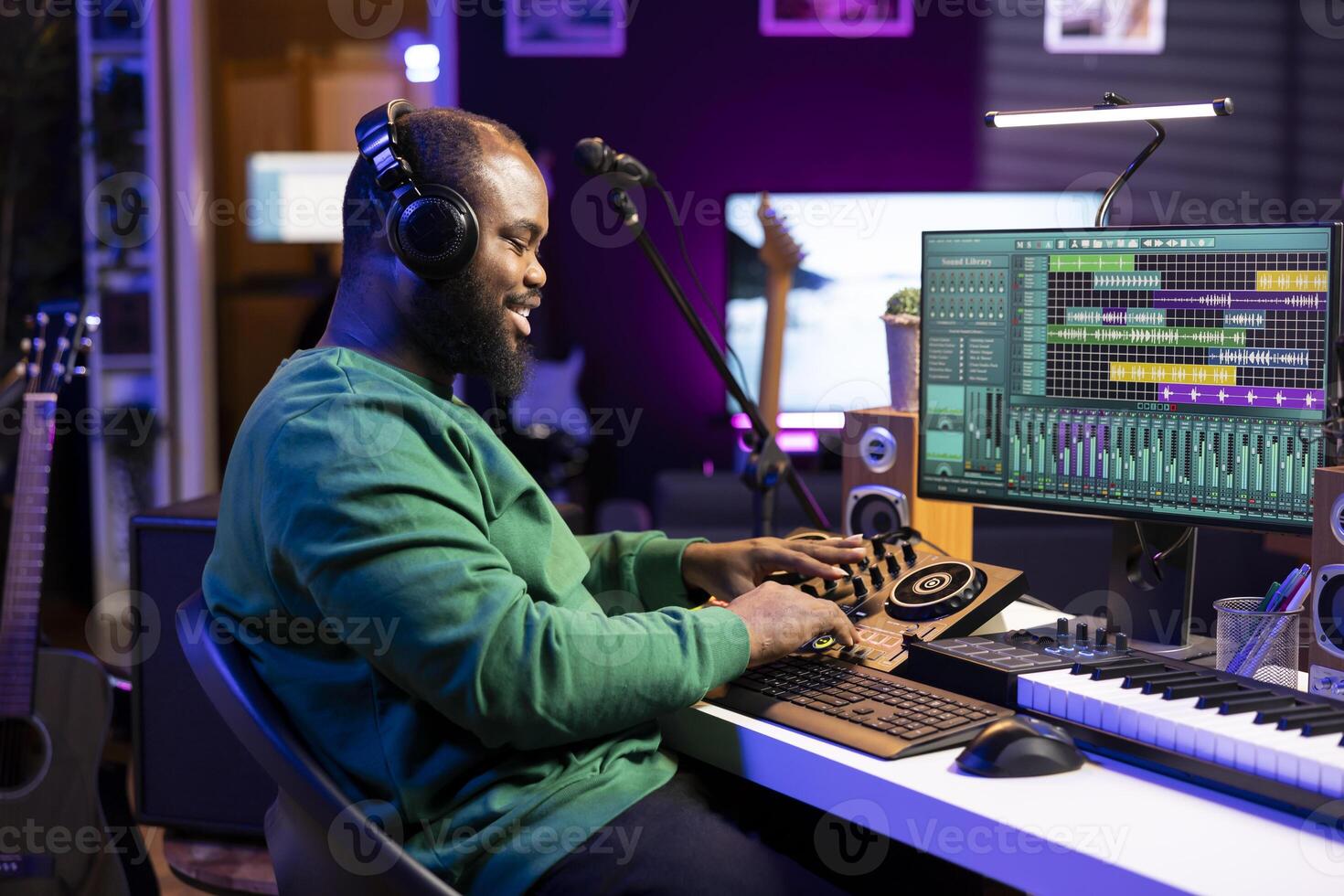 Confident music engineer working on mixing console in home studio, producing new sounds for a song and editing volume levels in daw software. Audio technician recording acoustic files. photo