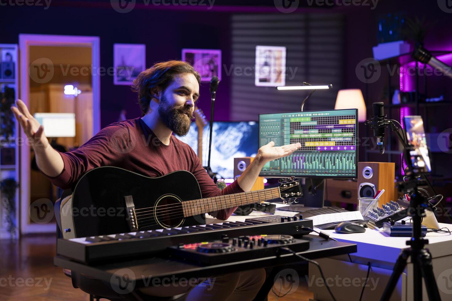 Songwriter recording himself in home studio singing and playing guitar, filming about learning to sing popular songs. Producer composer teaching online master class lessons on phone. photo