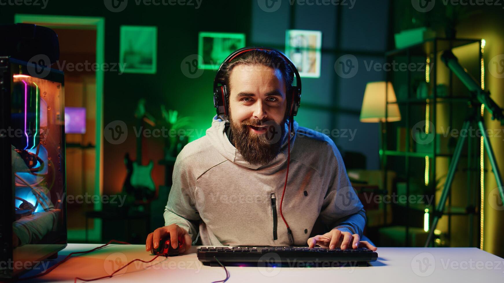 Esports player films himself playing videogames in front of internet fans during livestream, providing engaging commentary while battling foes. Zoom out shot of pro gamer streaming gaming session photo