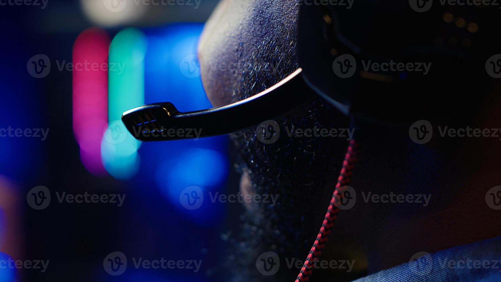 Close up of headset mic used by professional streamer competing in intense online multiplayer videogame live from home. Focus on headphones microphone used by man playing on gaming PC, camera A photo