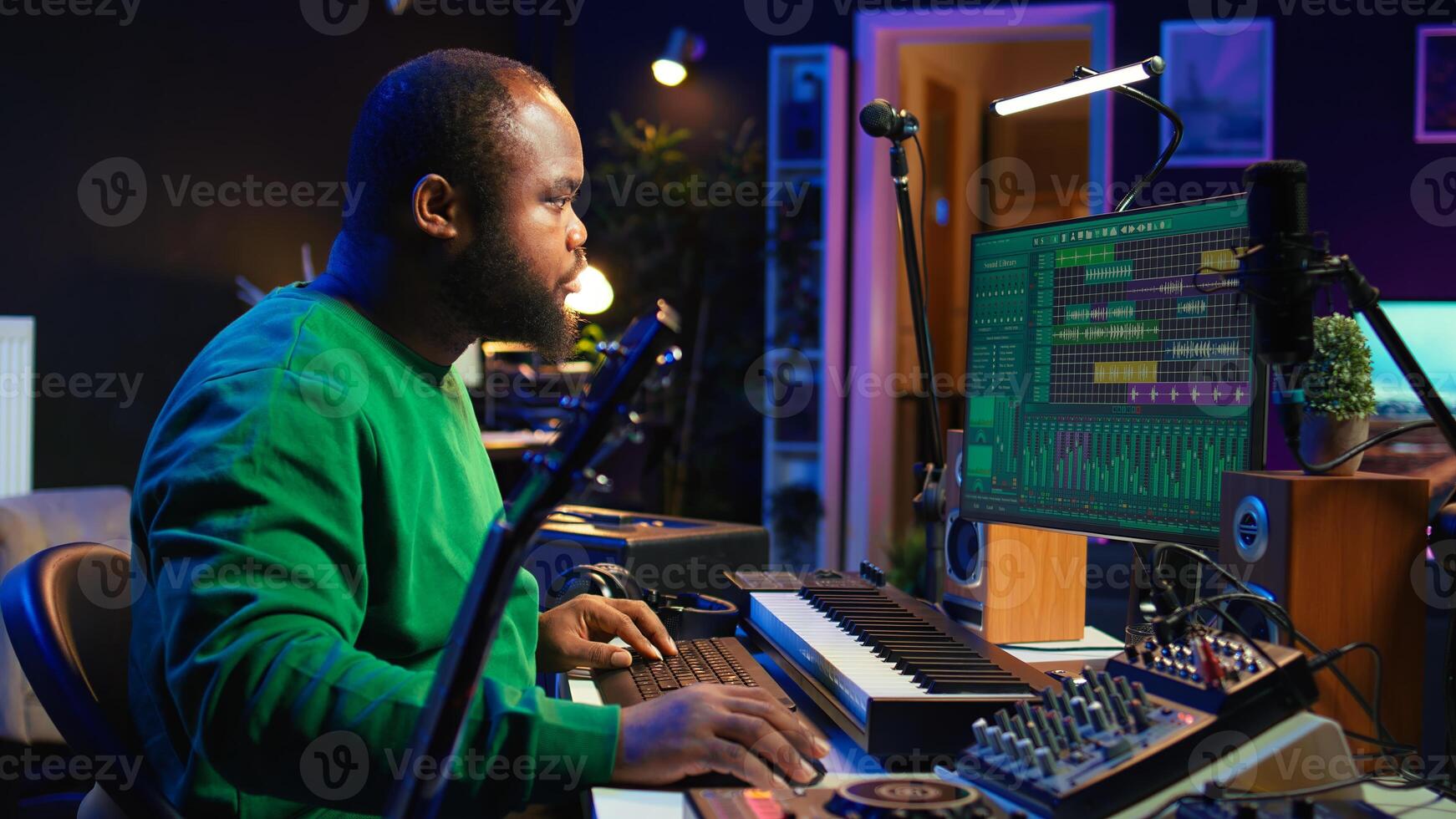Creative songwriter singing a melody and playing guitar, signal processing technology with digital audio software. Artist producer creating music with acoustic instrument and console. Camera B. photo