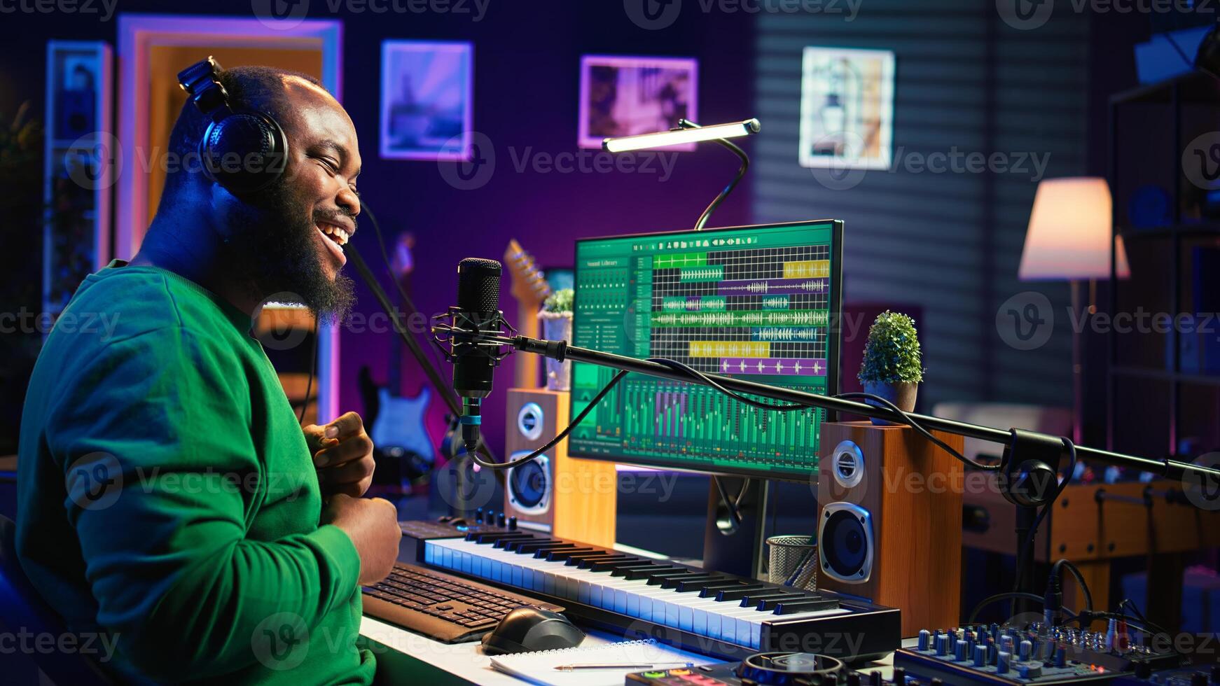 Confident songwriter performing a tune on microphone in home studio, recording his song and editing in post production. Performer artist singing aloud and using stereo equipment. Camera B. photo